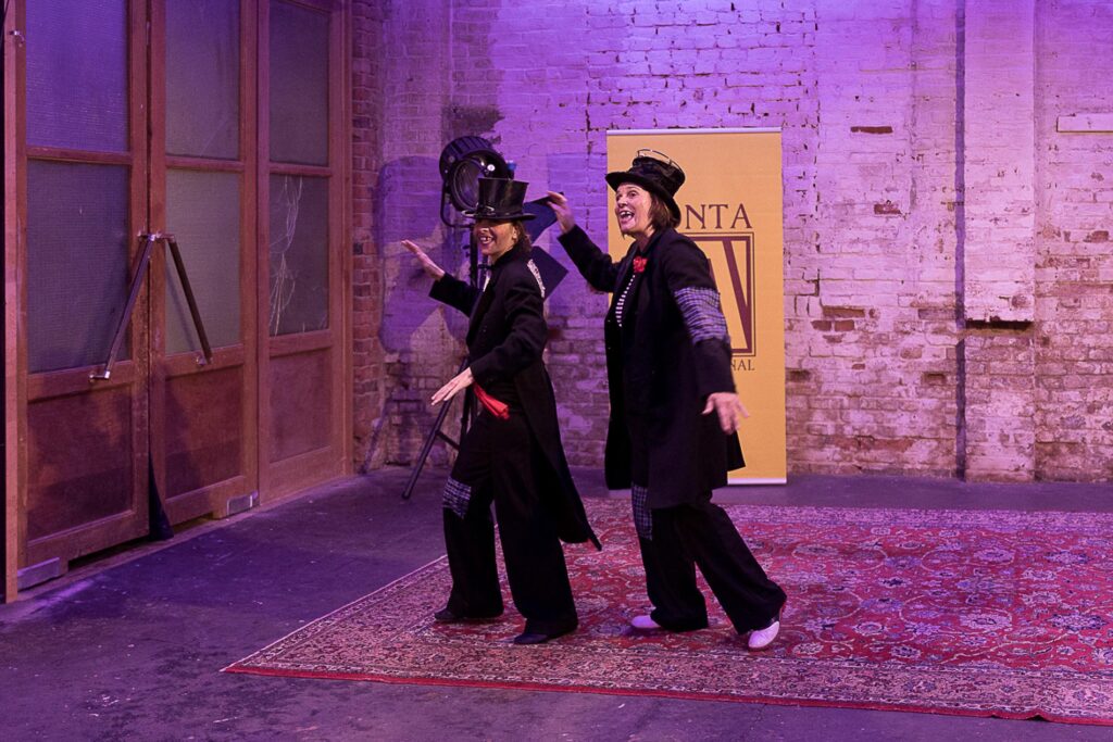 Das Bild zeigt zwei Clowns der Clown Doktoren. Sie tanzen und tragen schwarze Anzüge mit Zylinder. Im Hintergrund sieht man das Set des Zonta Benefits Livestreams im Schaerferaum, dem Mietstudio für Live Events, Amateur Fotografen und Kreative in Bad Homburg, Frankfurt und dem RheinMain Gebiet.